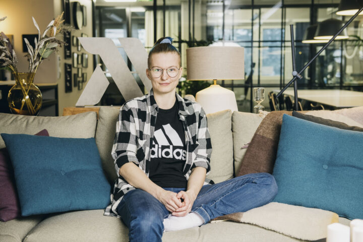 Noora Kukkonen istuu rennosti Monadin toimistolla hymyillen. Hän on ohjelmistokehittäjä, joka arvostaa uusia teknologioita ja merkityksellisiä projekteja.